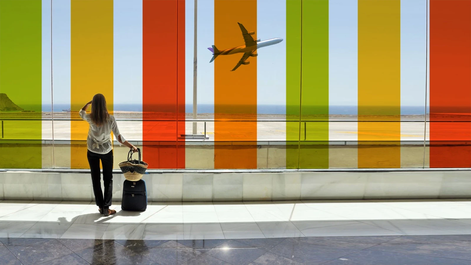 Quelqu'un qui regarde un avion décoller à travers une vitre couvertes de bandes de couleurs