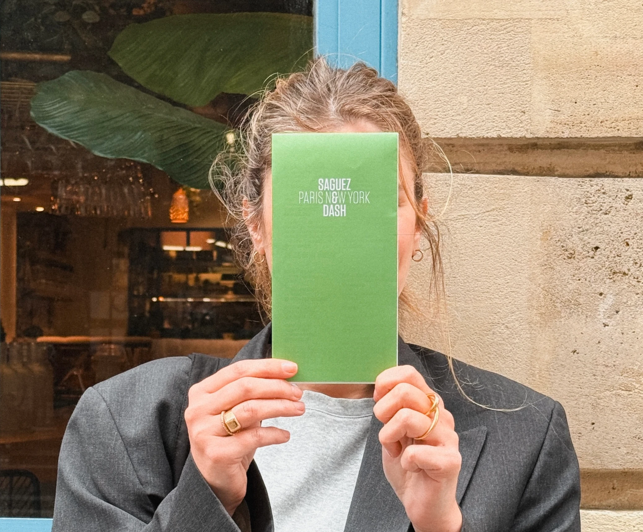 Photo d'une personne tenant la carte Saguez & Dash, qui regroupe le meilleur des adresses à Paris et New York.