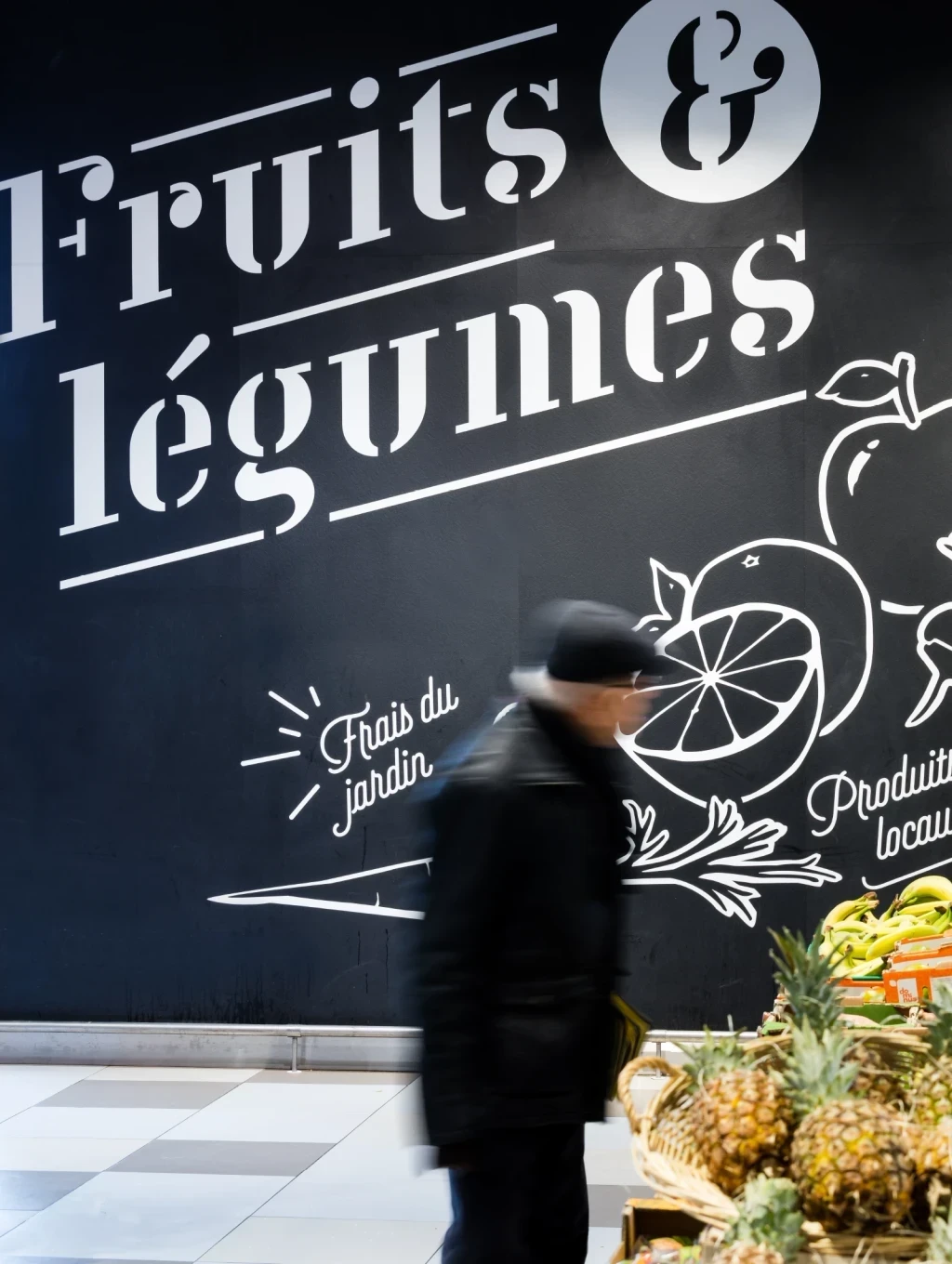 Mur intérieur d’un hypermarché E.Leclerc peint en noir avec texte blanc indiquant le rayon fruits et légumes.