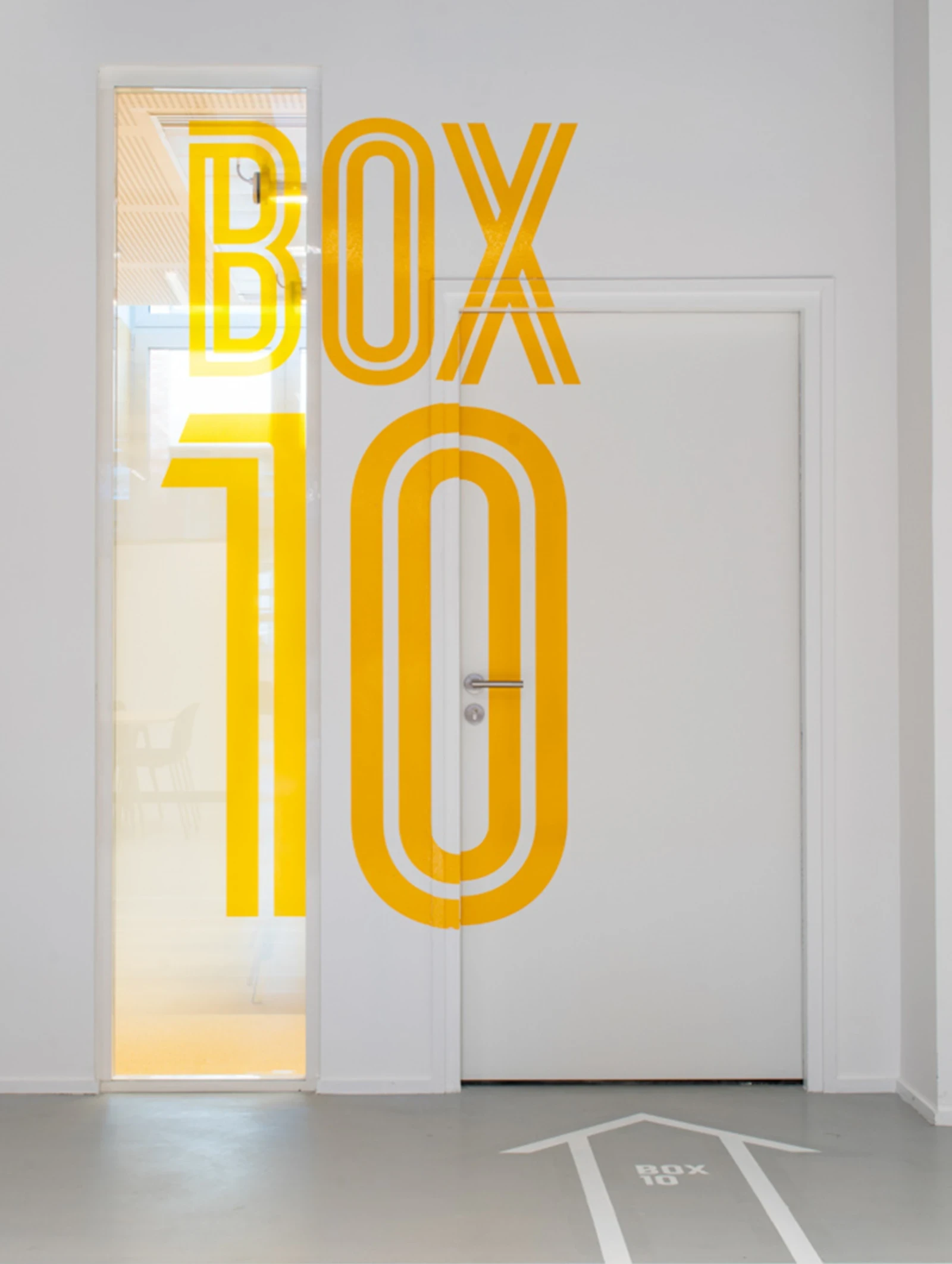 Box 10, typographie jaune sur le mur et une porte